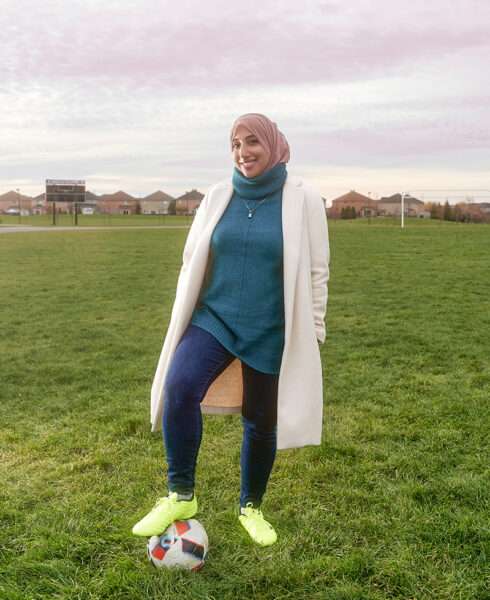 Shireen Ahmed stands on a soccer field with one foot on a soccer ball.